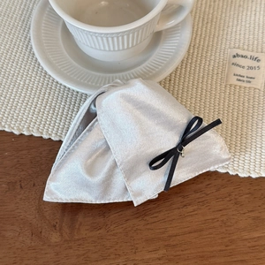 Détail d'une pince à cheveux en satin gris avec nœud noir sur une table en bois rustique