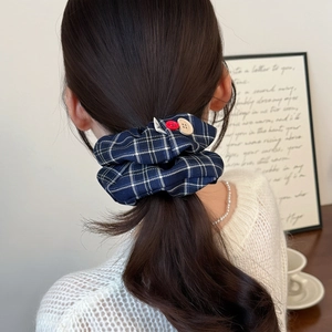 Classic blue and white plaid scrunchie with button accents worn on a low ponytail