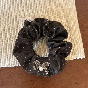 Détail du chouchou à pois avec un petit nœud et une perle sur un tapis tressé