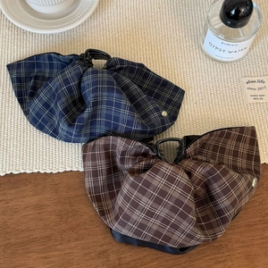 British style plaid bow hair clips in navy blue and coffee colors on a woven mat