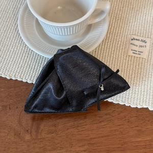 Détail d'une pince à cheveux noire scintillante avec nœud élégant et charme en métal