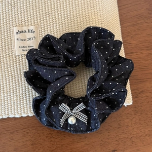 Détail d'un chouchou bleu à pois avec nœud pied-de-poule et élégante perle