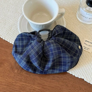Close-up of blue plaid fabric hair claw clip with pleated texture and multi-tooth grip