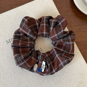 Macro detail of vintage plaid scrunchie with buttons and woven fabric texture on linen