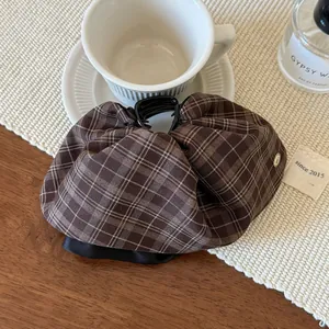 Detail of British plaid fabric hair claw clip with golden button on a cozy wooden table