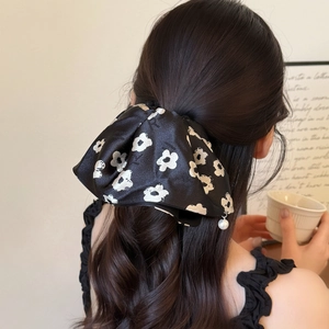 Elegant black satin hair claw with white floral print and pearl pendant on ponytail