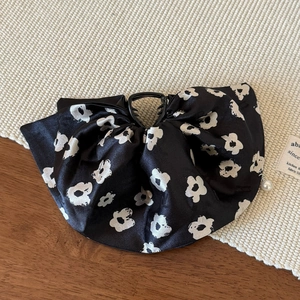 Close-up of black satin hair claw clip with white flower print and pearl pendant