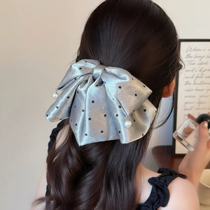 Silver satin bow hair claw with black polka dots and pearls on dark curly hair