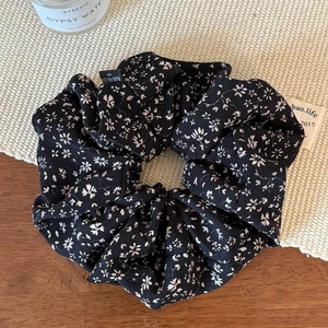 Vue détaillée du chouchou à motif floral avec texture en mousseline sur fond en bois