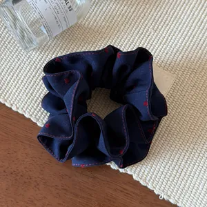 Detailed view of navy blue scrunchie with red hearts and contrast edge stitching