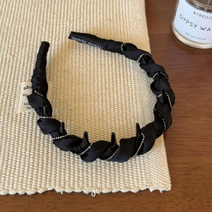 Détail du serre-tête en satin noir torsadé avec dents antidérapantes et perles fines