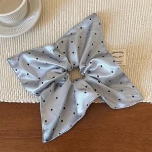 Detail of light blue satin scrunchie with black polka dots and wavy pleated edges