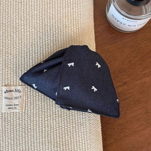 Detail of dark blue denim hair claw with white rabbit embroidery and twill texture