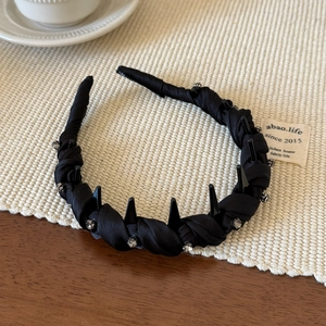 Détail du serre-tête en tissu noir orné de strass brillants avec des dents antidérapantes