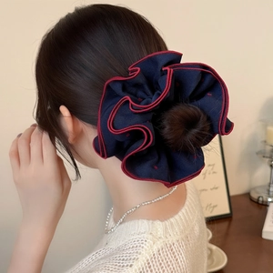 Navy blue oversized heart dot scrunchie hair tie with red trim shown on a bun
