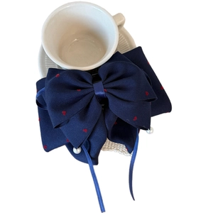 Fiocco per capelli blu scuro con cuori rossi e pendenti di perle su piatto in ceramica