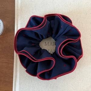 Detail view of navy blue scrunchie with red heart pattern and contrast edge stitching