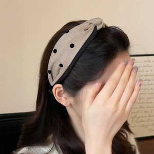 Detalle de la diadema vintage beige con lunares negros y textura de tela con nudo suave