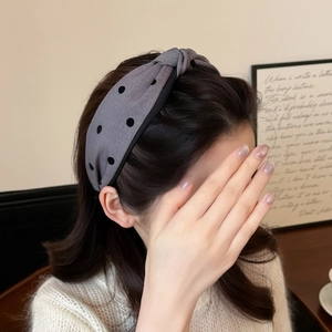 Primer plano de diadema gris de lunares con nudo superior y diseño de tela ancha