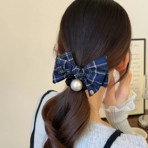 Elegant navy blue plaid bow scrunchie with pearl detail on a female model's ponytail
