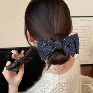 Détail du nœud bleu à pois et de l'élastique à perles sur les cheveux du modèle