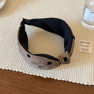 Detalle de una diadema anudada con lunares marrón café sobre un soporte tejido