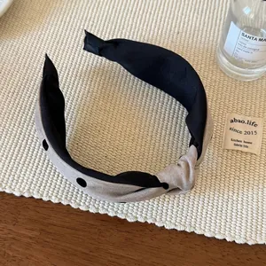 Detalle de una diadema con nudo y estampado de lunares en diseño bicolor de tela gris y negro