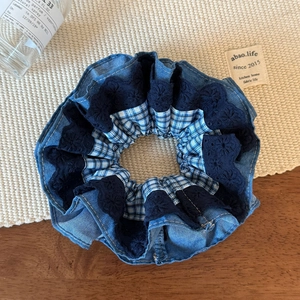 Detailed view of blue denim and plaid lace scrunchie on a rustic wooden background