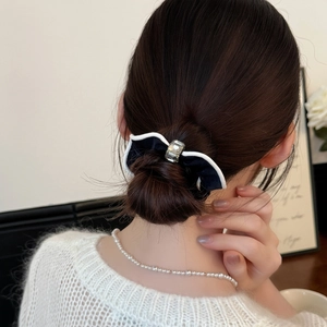 Chouchou noeud noir avec bordure blanche et cristal porté sur un chignon chic
