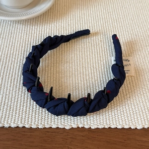 Dettaglio di un cerchietto in tessuto blu navy a pois rossi con denti antiscivolo
