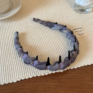 Detail of purple plaid headband with inner non-slip teeth on a woven mat background