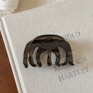 Vue détaillée d'une pince à cheveux marron foncé sur une surface de livre texturée