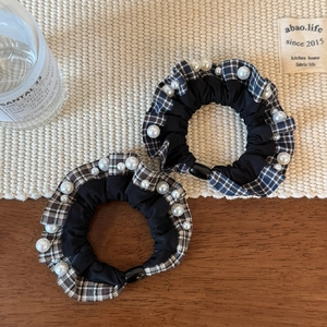 Detailed view of plaid scrunchies with white pearls on a rustic background