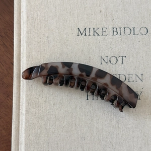 Detail of tortoise shell banana hair clip with secure teeth on a beige book surface