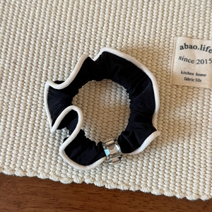 Détail d'un chouchou noir avec bordure ondulée blanche et perle de cristal élégante