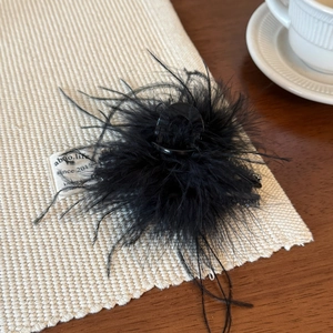 Détail d'une pince à cheveux élégante avec plumes noires et strass raffinés
