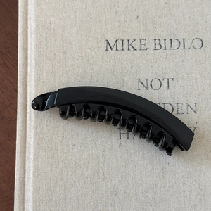 Close-up of glossy black banana hair clip with interlocking teeth for high ponytail