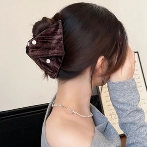Brown velvet bow hair claw clip with white polka dots shown on a woman's hair