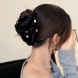 Elegant black velvet bow hair claw with white polka dots worn by a model in back view