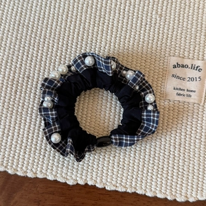 Close-up of vintage plaid scrunchie with white pearl accents on woven fabric