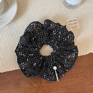 Close-up of hollow knit scrunchie with tweed texture and elegant pearl pin detail
