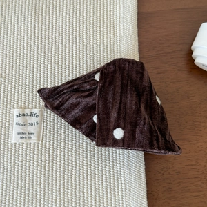 Detailed view of the dark brown velvet shark clip with elegant white polka dots pattern