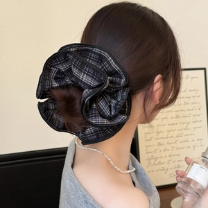 Detail of a large black and white checkered ruffle scrunchie styled on a low bun hair