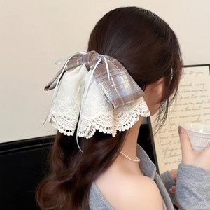 Elegant plaid lace bow hair clip in brown and beige displayed on a woman's hair