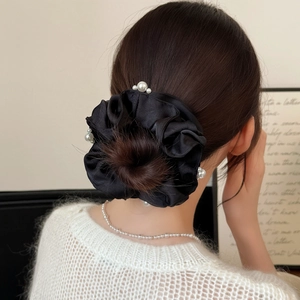 Elegant black satin hair scrunchie with pearls styled on a bun hairstyle for women