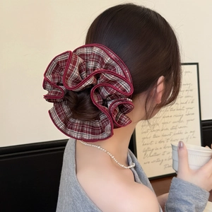 Plaid ruffle scrunchie in red and grey tartan pattern worn on a sophisticated updo