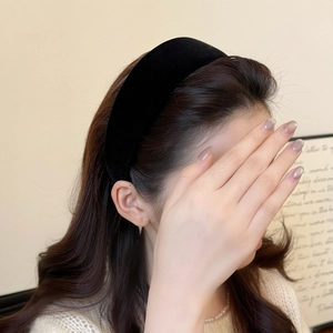 Close-up of a thick black velvet padded headband on a model for a stylish hair look