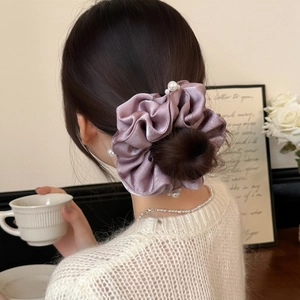 Elegant purple satin scrunchie with pearls on a model's hair bun, 45-degree angle
