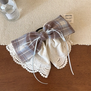 Close-up of vintage plaid bow hair clip with intricate white floral lace and delicate ribbons