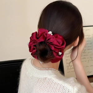 Detail of burgundy satin hair scrunchie with white pearls worn on a ponytail